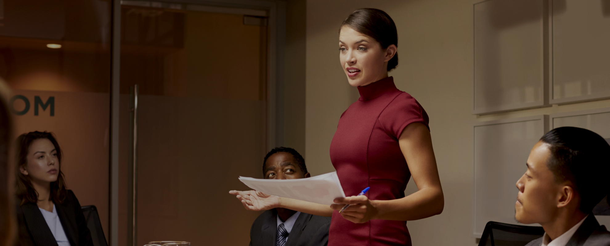 A professional setting with three individuals, faces obscured for privacy. One person stands presenting a document to two seated individuals across a table. The scene appears to be related to web design in Sri Lanka.