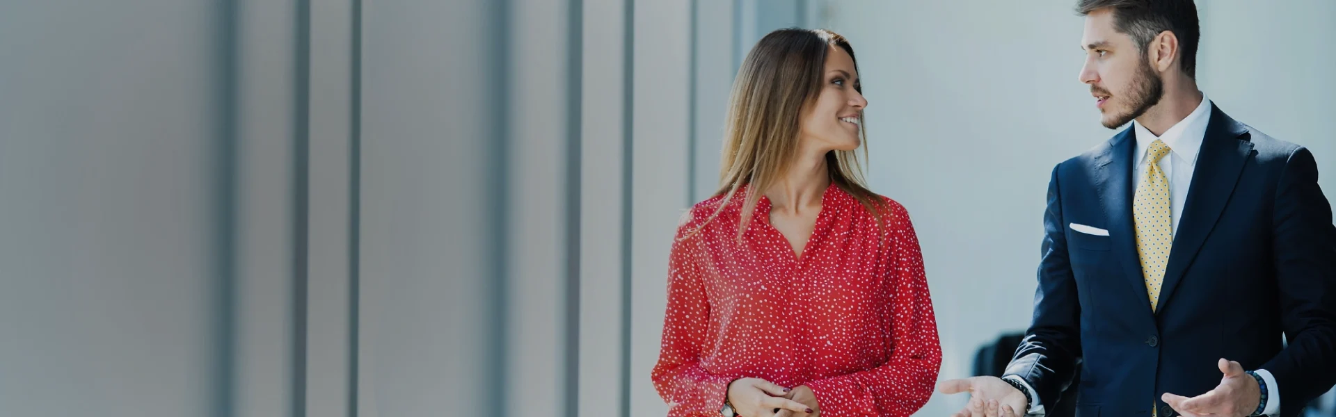 Two professionals in business attire engaging in a discussion against a blurred office backdrop, representing Weblook’s commitment to professional web design services in Sri Lanka.